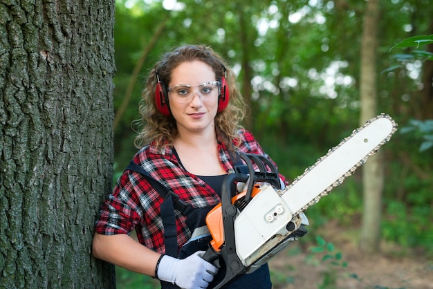 Free photo professional lumberjack in the forest cutting an oak trunk with chainsaw