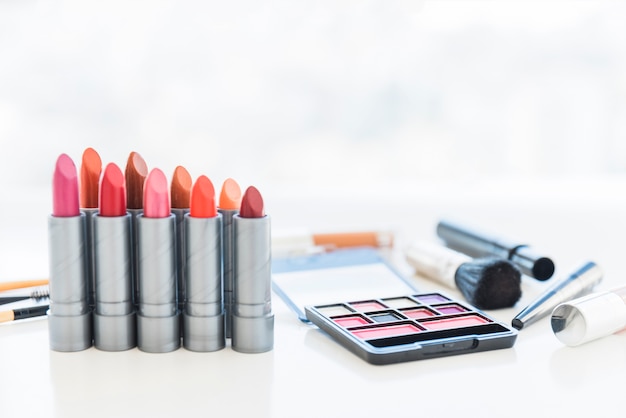 Free photo professional make-up tools with palette of cosmetic eye shadows and row of lipstick shades