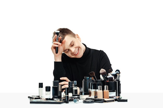 Free photo professional makeup artist with tools isolated on white studio background. the man in female proffesion. gender equality concept