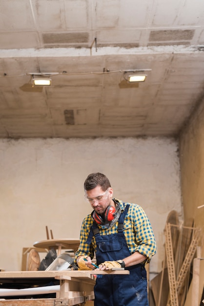 Free Photo professional male carpenter taking the measurement on workbench in workshop