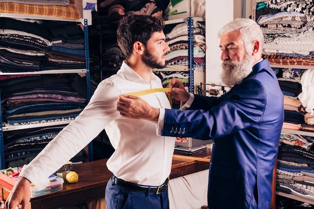 Professional male fashion designer taking measurement of his customer's chest