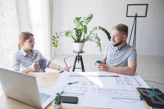 Professional male and female architecture discussing something while coffee break