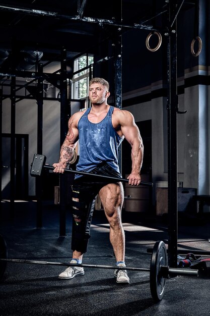 Professional powerlifter with a bandage on a leg, holding a sports hammer, warming up before training, injury recovery. Sport, commitment, motivation