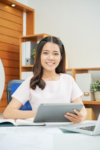 Professional smiling woman with tablet at desk