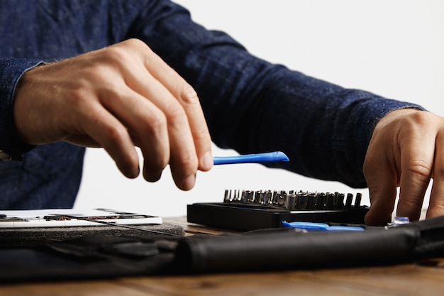 Free photo professional takes speciall opening plastic instrument from his tool bag to repair tablet