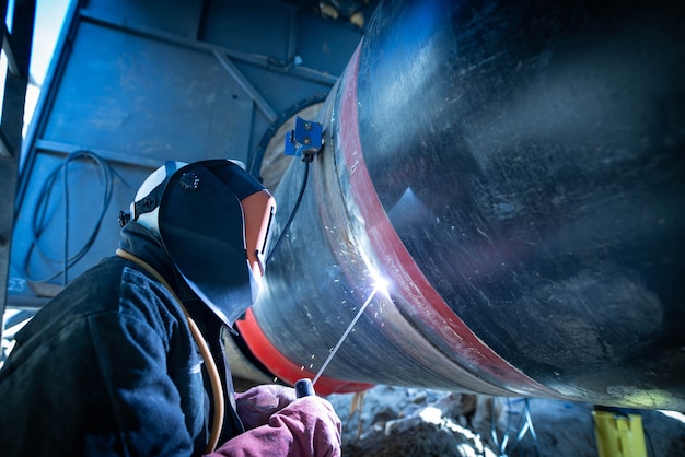 Free photo professional welder welding pipe on a pipeline construction