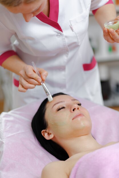 Professional woman applying green cream with a brush