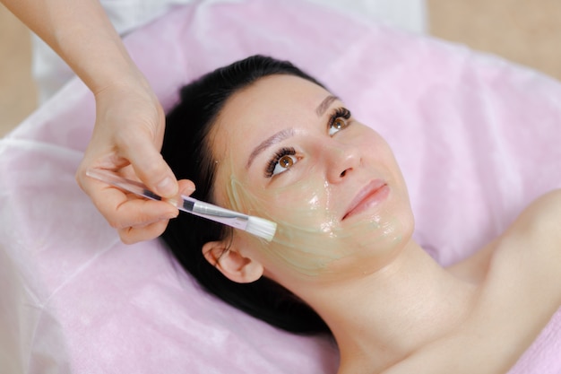 Professional woman applying green cream with a brush