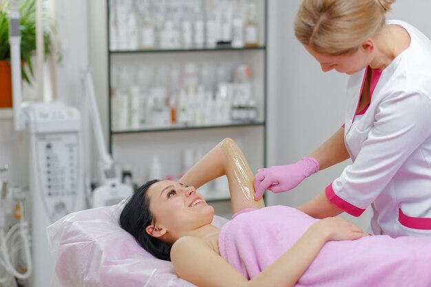 Professional woman making wax another woman in the arm