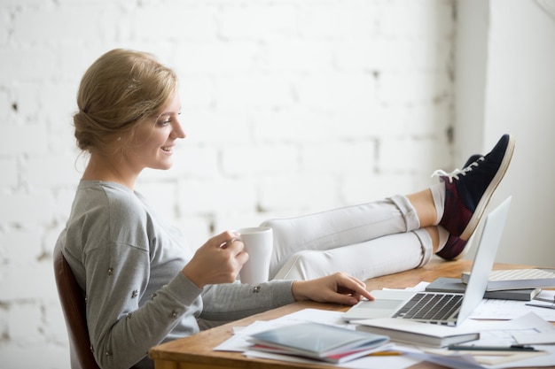 Profile portrait of student girl with her legs on desk