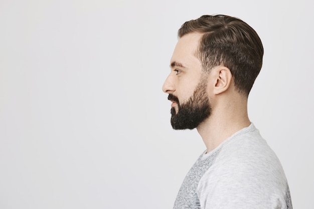 Profile of stylish bearded man made new hairstyle at barber shop