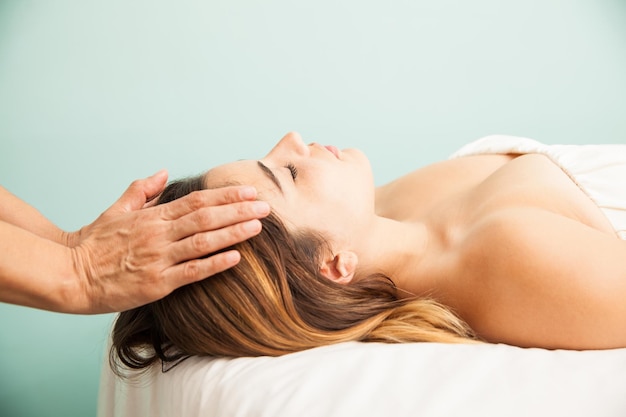 Free photo profile view of a cute young woman getting her energy balanced at a reiki session in a health clinic and spa