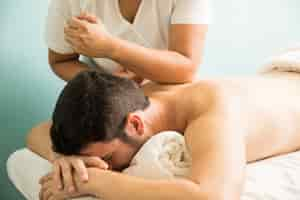 Free photo profile view of a young man getting a lomi lomi massage in a spa clinic