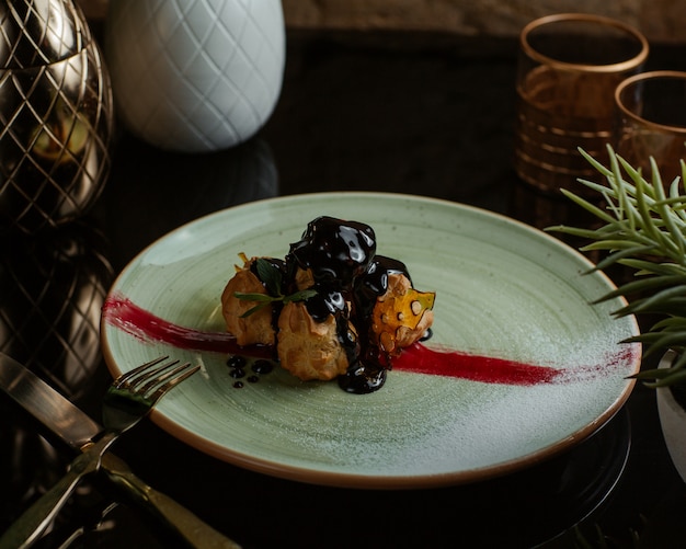 Free Photo profiteroles in chocolate sauce inside white plate.