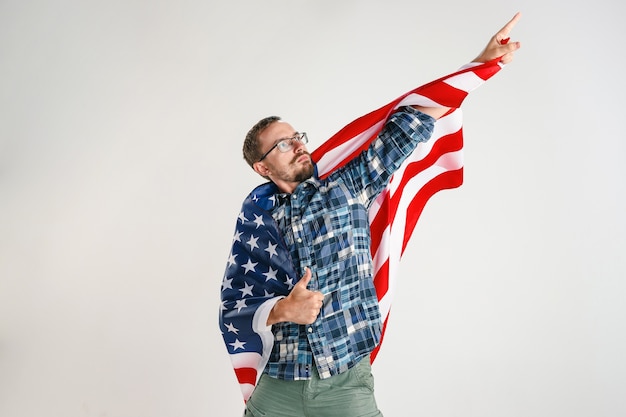 Proud young man holding flag of the United States of America isolated on white studio.