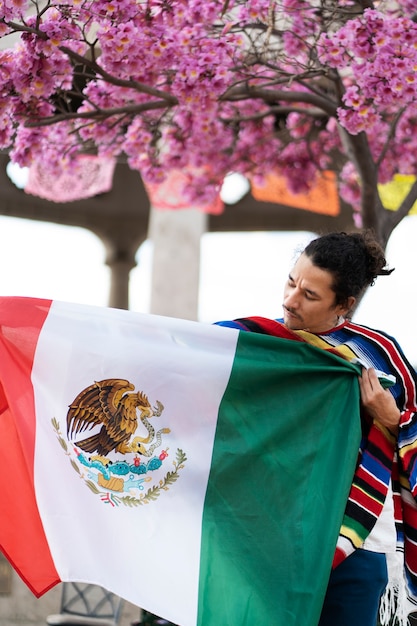 Proud young man holding mexican flag medium shot