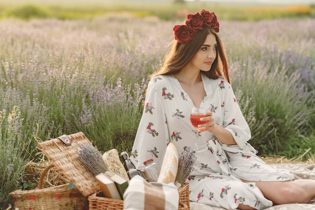 Provence woman relaxing in lavender field. Lady in a picnic. Woman in a wreath of flowers.