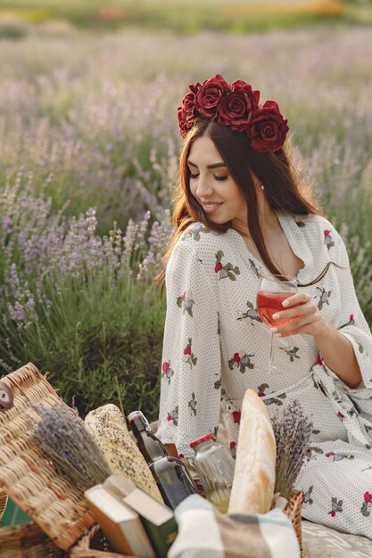 Provence woman relaxing in lavender field. Lady in a picnic. Woman in a wreath of flowers.