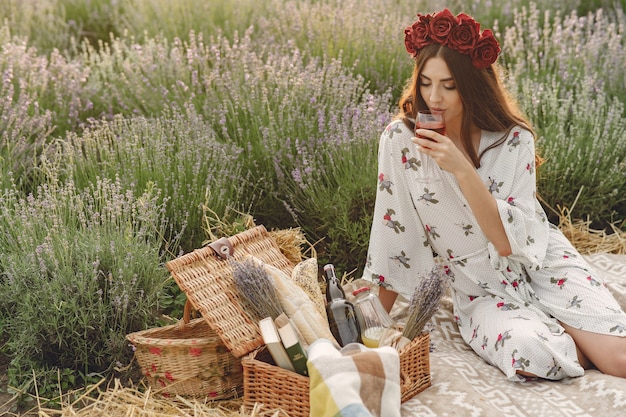 Provence woman relaxing in lavender field. Lady in a picnic. Woman in a wreath of flowers.