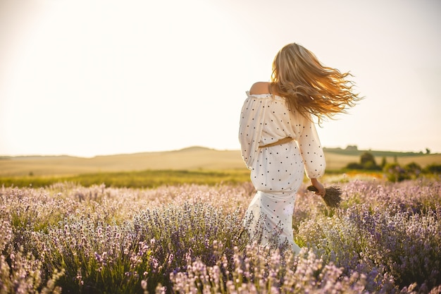 Provence woman relaxing in lavender field. Lady in a white dress. Girl with bouquete of flowers.