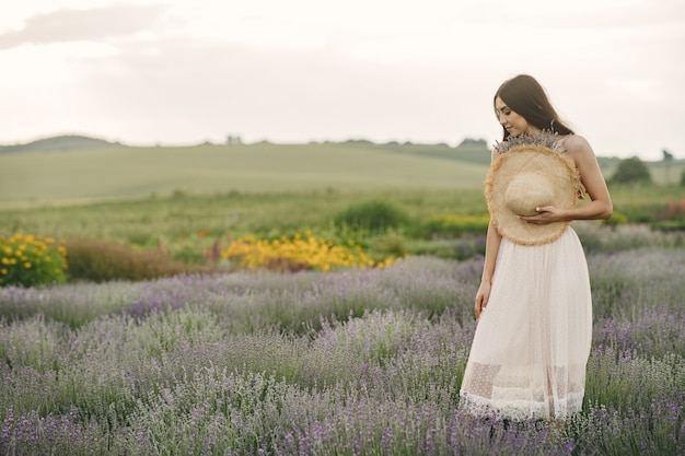 Provence woman relaxing in lavender field. Lady with a straw hat.