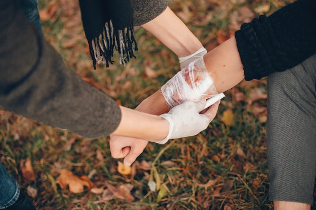 Free Photo providing first aid in the park. man bandaged  injured arm. guy helps a friend.