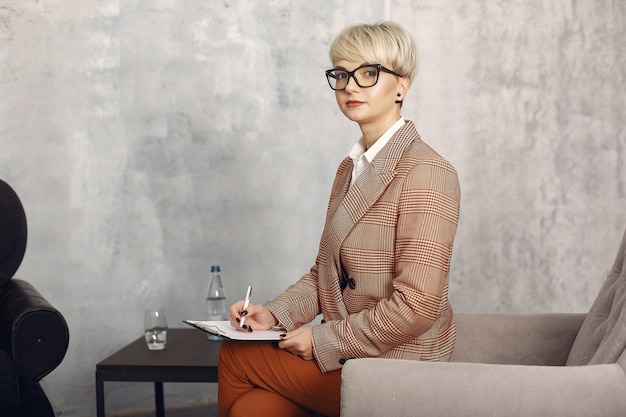 Free photo psychologist with glasses sitting on a chair at the office