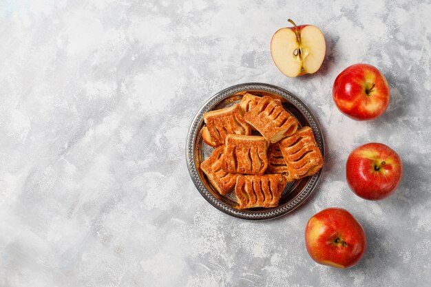 Puff pastry cookies filled with Apple jam and fresh red apples on light concrete 