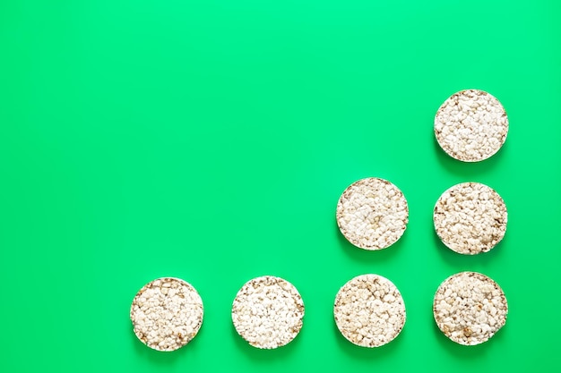 Free photo puffed rice cakes on green background flat lay copy space