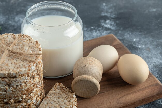 Puffed rice cakes, milk and eggs on wooden board