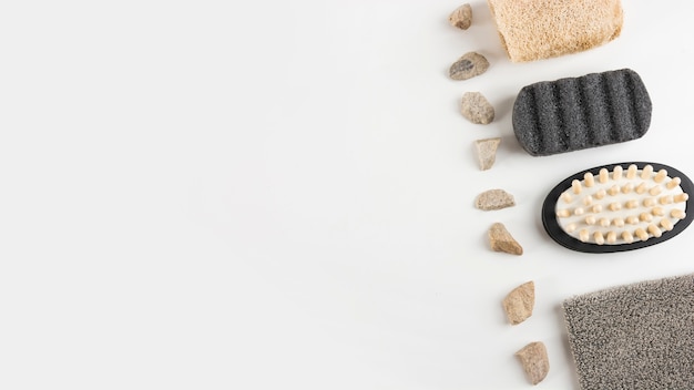 Pumice stone; massage brush; loofah and spa stones arranged in row on white background