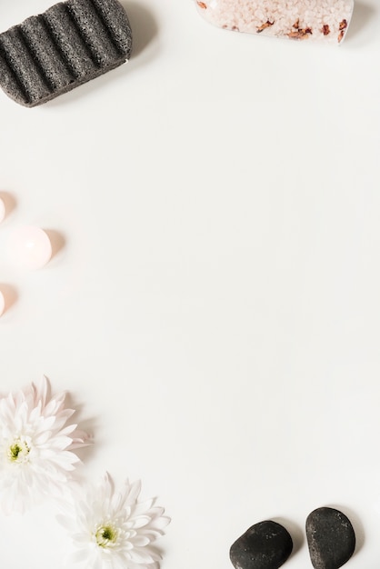 Free photo pumice stone; salt; la stone; candles and flower on white background