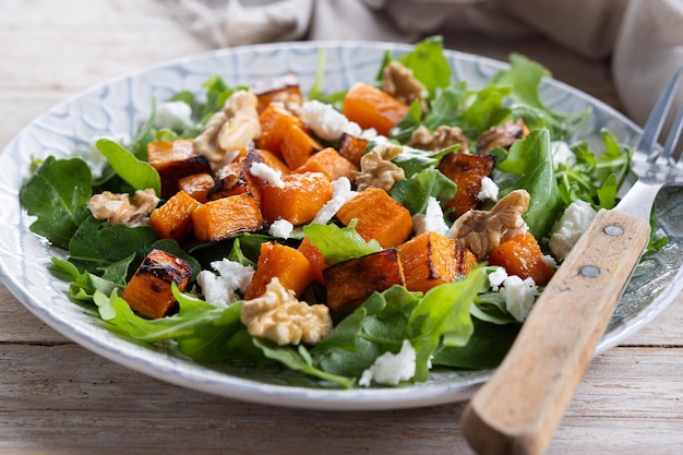 Free photo pumpkin salad with walnuts and feta cheese on wooden table