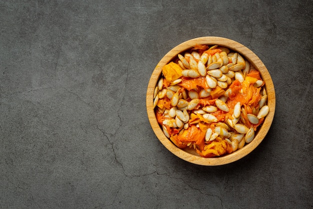 Free photo pumpkin seed put in wooden bowl placed on a dark floor