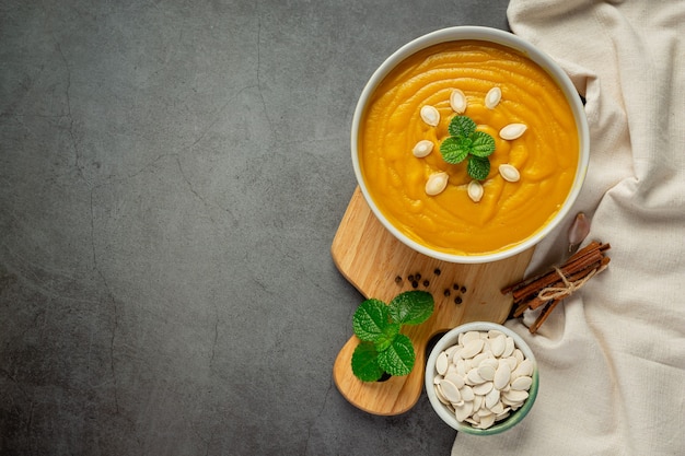 Pumpkin soup in white bowl placed on wooden cutting board