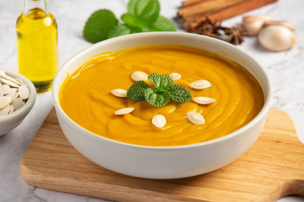 Free photo pumpkin soup in white bowl placed on wooden cutting board