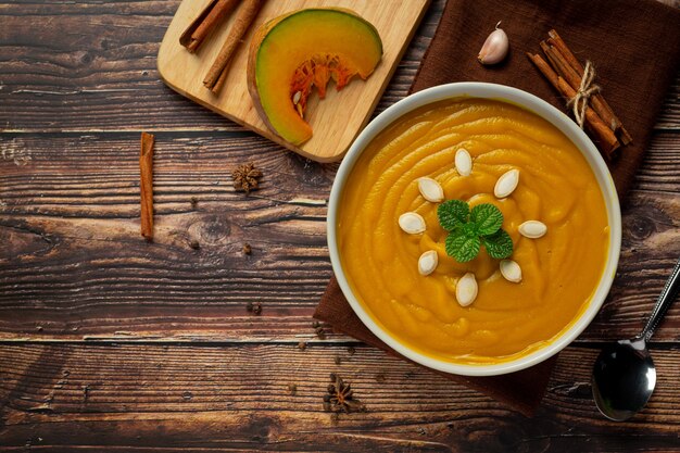 Free photo pumpkin soup in white bowl placed on wooden floor