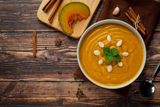 Pumpkin soup in white bowl placed on wooden floor