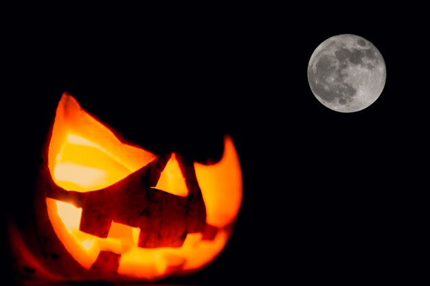 Pumpkin with light inside on a dark background and moon next