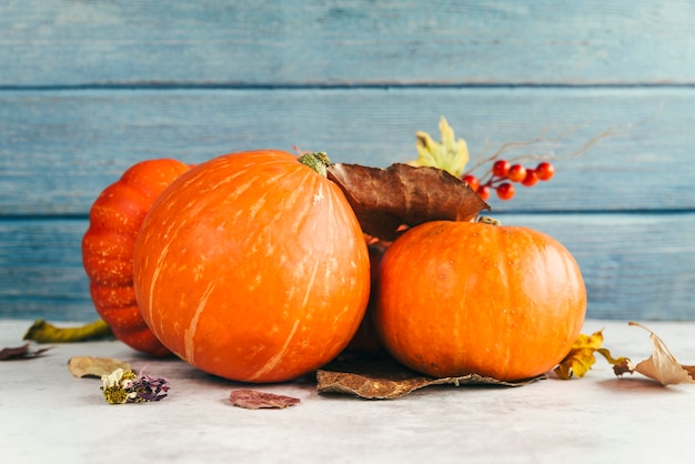 Free photo pumpkins with leaves on table