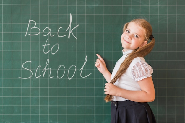 Pupil pointing at back to school inscription on chalkboard