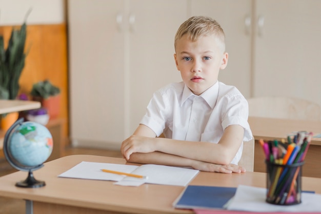 Pupil sitting with hands on desk in classroom