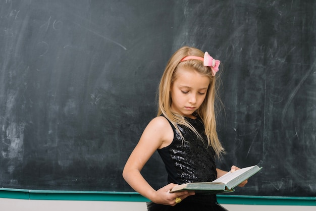 Free photo pupil with book at chalkboard