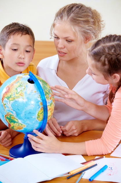 Pupils looking at globe while listening to teacher