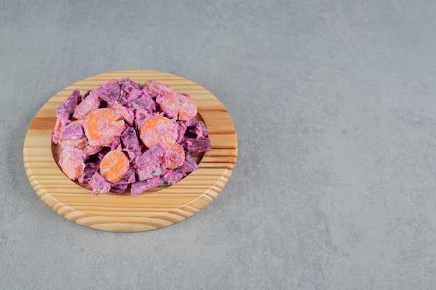 Purple beetroot and carrot salad on a wooden board.