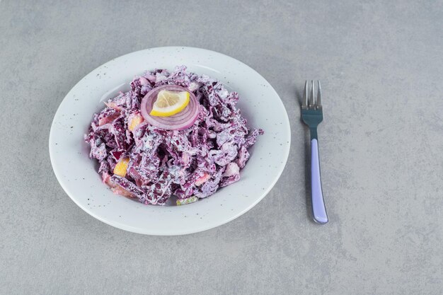 Purple cabbage and onion salad in a white ceramic plate.