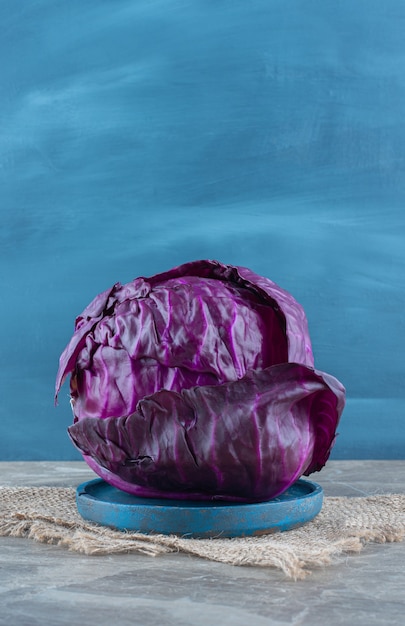 Purple cabbage on the wooden plate, on the trivet , on the marble table. 