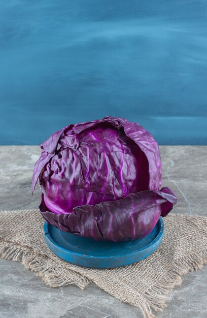 Purple cabbage on the wooden plate, on the trivet , on the marble table. 