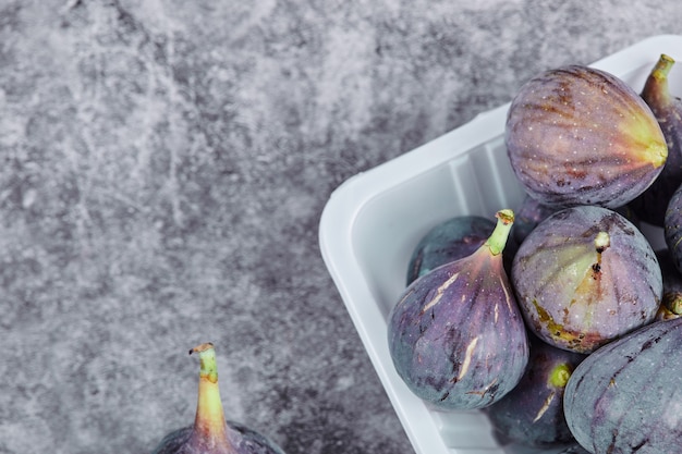 Free Photo purple figs in a white plastic container.