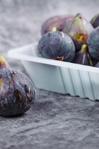 Free photo purple figs in a white plastic container.